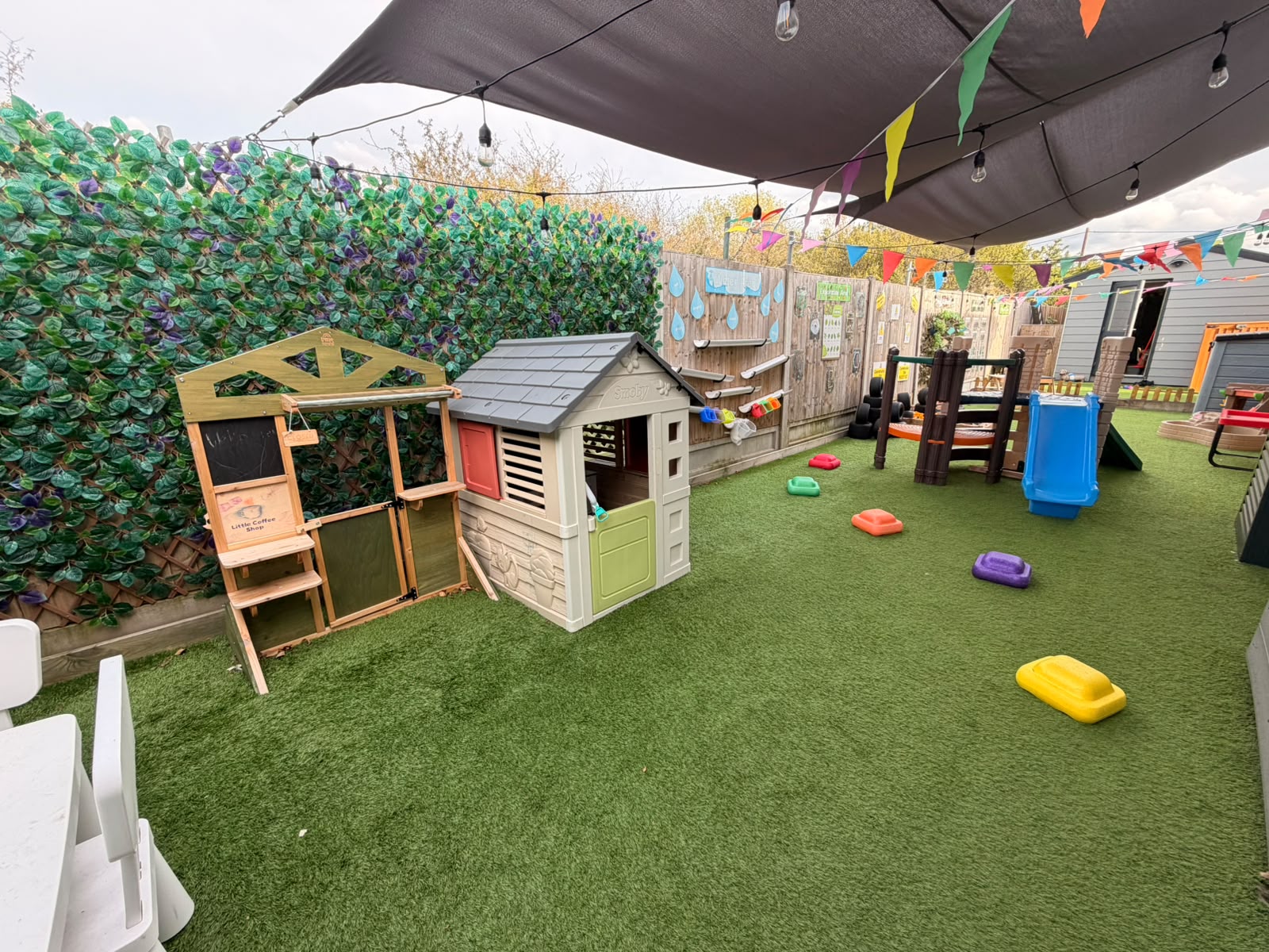 A wide view of the Basildon garden with play house, climbing frame and shaded play space